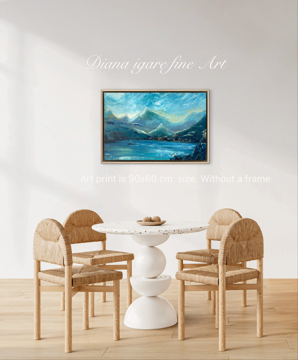 A framed landscape art print depicting blue mountains and a lake, displayed on a white wall above a dining table and chairs. Text overlays read 'Diana igare fine Art' and 'Art print is 90x60 cm - Without a frame'.